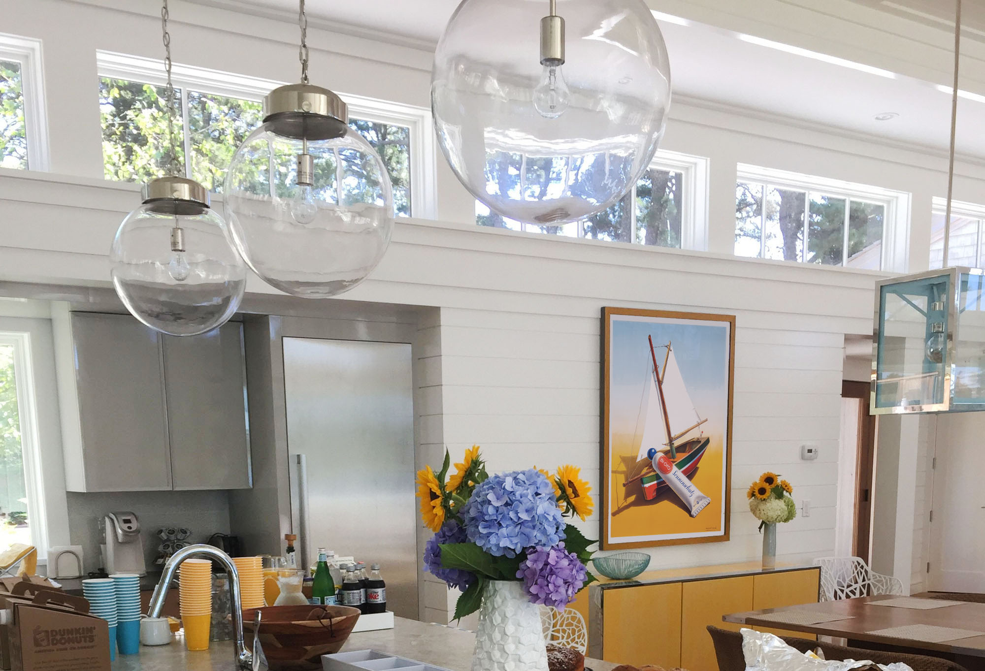 framed poster of toy ship and paint tube in modern kitchen; white, grey, blue, yellow, brown